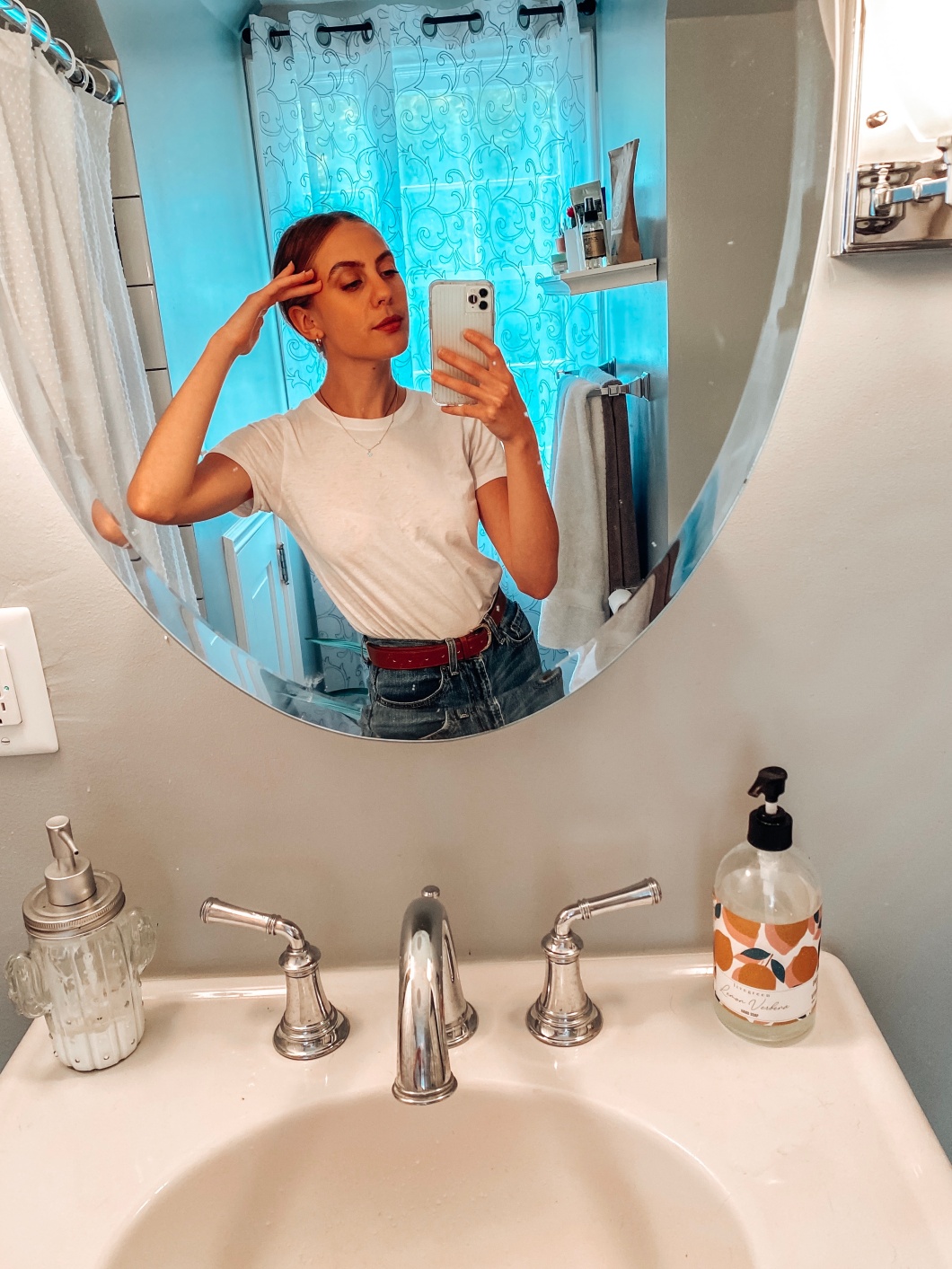 Candace taking a mirror selfie in front of her bathroom sink.